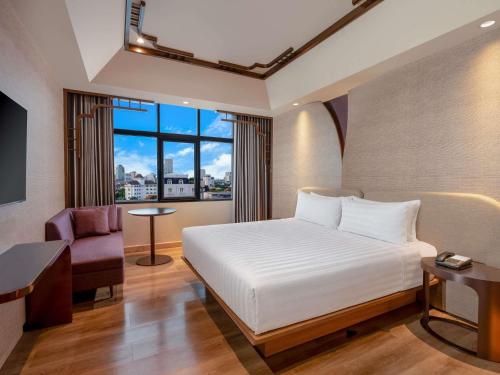 a bedroom with a bed and a desk and a window at Mercure Surabaya Grand Mirama in Surabaya