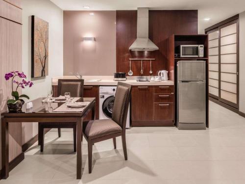 a kitchen with a table and a refrigerator and a stove at Grand Mercure Bangkok Asoke Residence in Bangkok