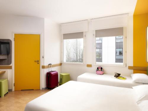 a bedroom with two beds and a yellow door at ibis budget Warszawa Centrum in Warsaw
