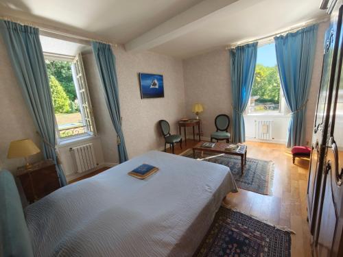a bedroom with a white bed and blue curtains at Château de la Moissetie in Aurillac