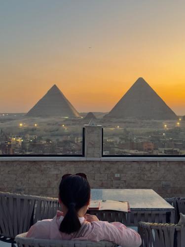 a woman sitting at a table looking at the pyramids at Continental Pyramids INN & Roof Top in Cairo