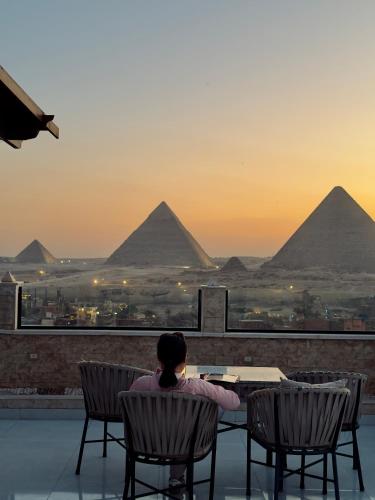 a woman sitting at a table looking at the pyramids at Continental Pyramids INN & Roof Top in Cairo