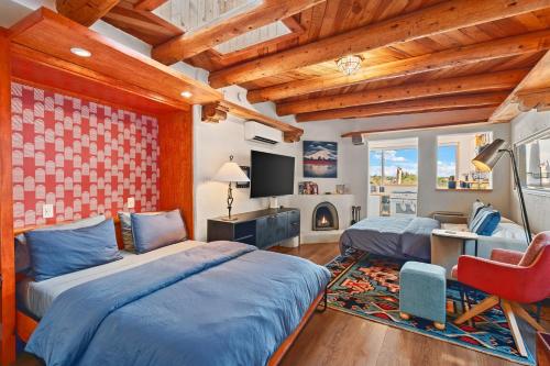 a bedroom with two beds and a tv and a chair at Restored Adobe Casita Big Views Walk to Plaza in Santa Fe
