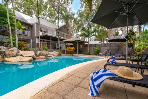 a hat sitting on a bench next to a swimming pool at Paradise On The Beach Resort in Palm Cove