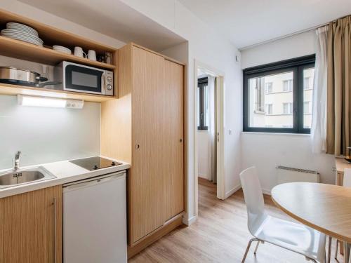 a kitchen with a sink and a table and a table and chairs at Aparthotel Adagio Access Bruxelles Europe Aparthotel in Brussels