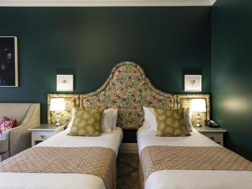 a bedroom with two beds and a green wall at Grand Mercure Basildene Manor in Margaret River Town