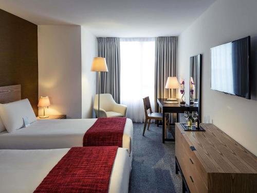 a hotel room with two beds and a desk at Mercure Montevideo Punta Carretas in Montevideo