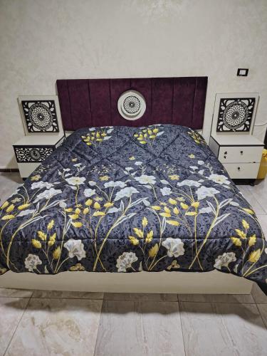 a bed with a blue comforter with flowers on it at الرائد للشقق المفروشة in Amman