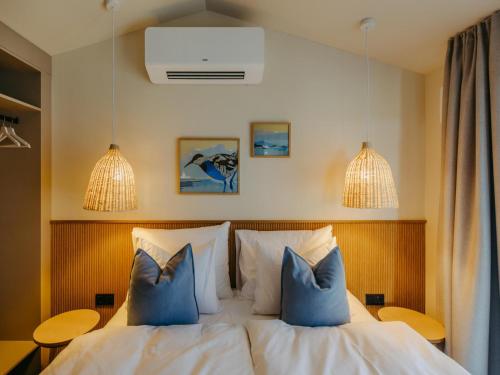 a bedroom with a white bed with blue pillows at Guesthouse Seeblick in Breitenbrunn