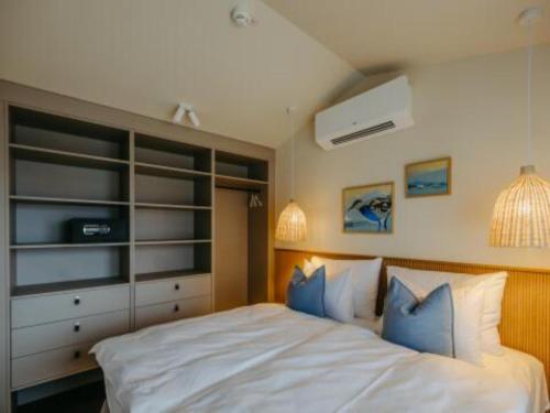 a bedroom with a large white bed with blue pillows at Guesthouse Leithagebirge in Breitenbrunn