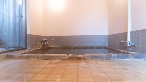 a bath tub in a bathroom with a dog in it at くつろぎと料理の御宿花さと -Hanasato- in Minamiizu