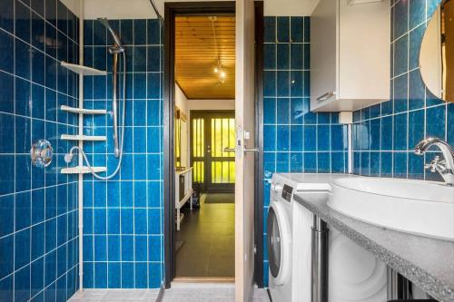 a blue tiled bathroom with a sink and a washing machine at 7041-Bogo-By-Tarnbakken-21 in Bogø By
