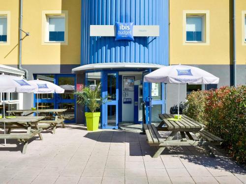 a group of tables and umbrellas in front of a building at ibis budget Issoire in Issoire
