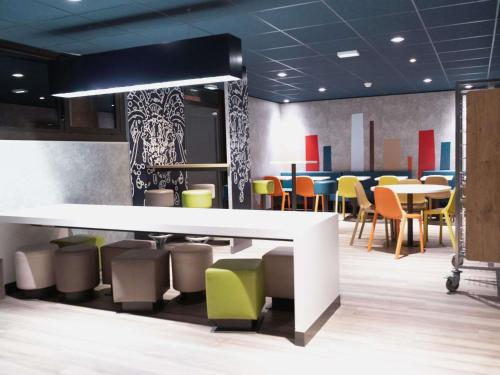 a dining room with colorful chairs and tables at ibis budget Thonon Les Bains in Thonon-les-Bains