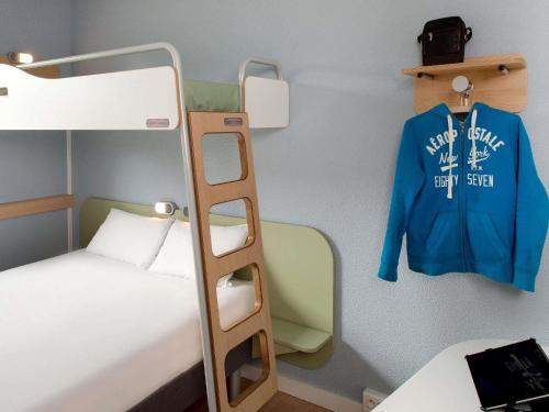 a bunk bed with a blue jacket hanging on a wall at ibis budget Montceau les Mines in Montceau-les-Mines