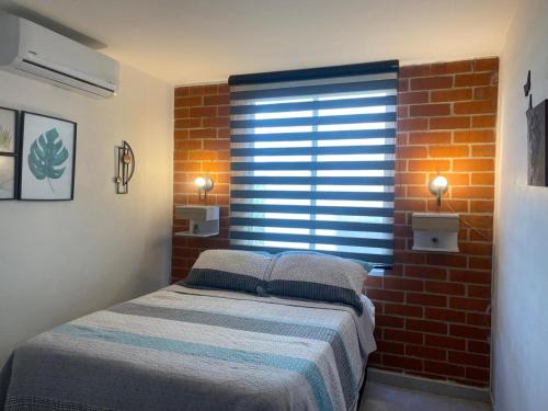 a bedroom with a bed and a brick wall at Reservas del peñon in Girardot