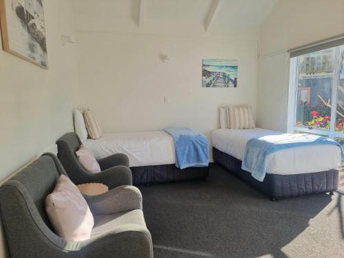 a bedroom with two beds and a couch and a window at Ohope Beach Motel in Ohope Beach