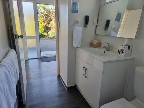 a white bathroom with a sink and a mirror at Ohope Beach Motel in Ohope Beach