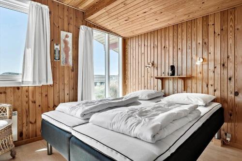a large bed in a room with wooden walls at 4468-Hvide-Sande-Tingodden-427 in Hvide Sande