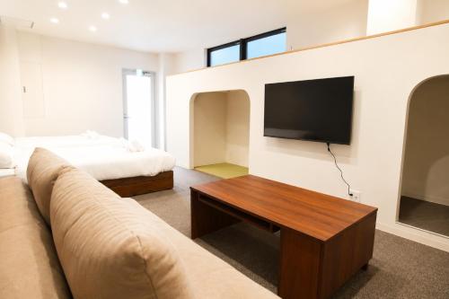 a living room with a couch and a flat screen tv at Tsunagu森ノ宮 in Osaka