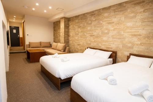 a hotel room with two beds and a couch at Tsunagu森ノ宮 in Osaka