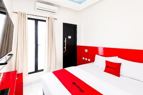 a bedroom with a red and white bed and a window at RedDoorz @ Galuh Mas in Karawang