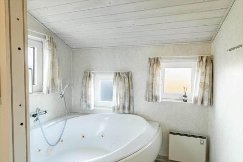 a white bath tub in a bathroom with two windows at G143-Lemvig-Syrenvej-43 in Lemvig