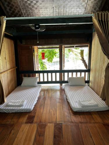 two beds in the middle of a room with wooden floors at Rocky Eco House in Na Hang