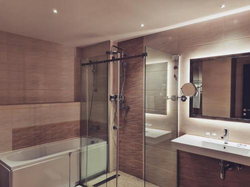 a bathroom with a shower and a tub and a sink at Mercure Tetovo in Tetovo