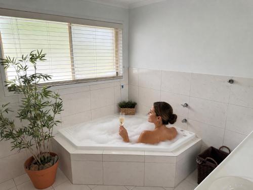 a woman sitting in a bath tub with a candle at Palacete Beach - Resort Style Stay in Culburra Beach