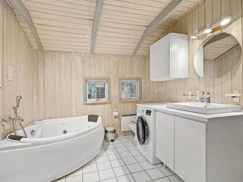 a bathroom with a tub and a sink and a washing machine at 0048-Romo-Trinnesvej-12 in Høm