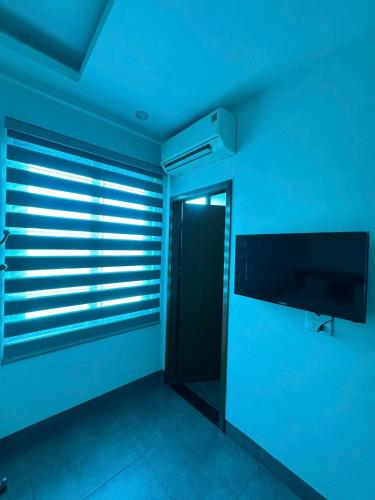 a blue room with a television and a window with blinds at Hoàng Long Hotel 