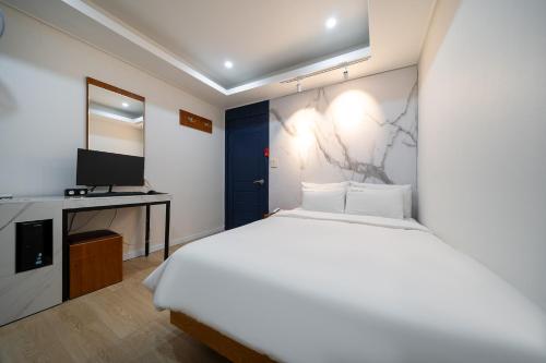 a bedroom with a white bed and a television at Yeon Stay in Seoul