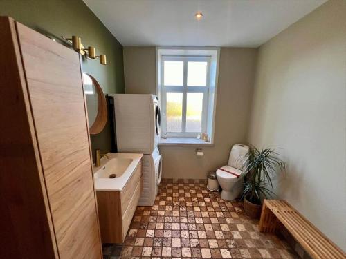 a bathroom with a sink and a toilet and a window at 0057-Romo-Juvrevej-49 in Høm