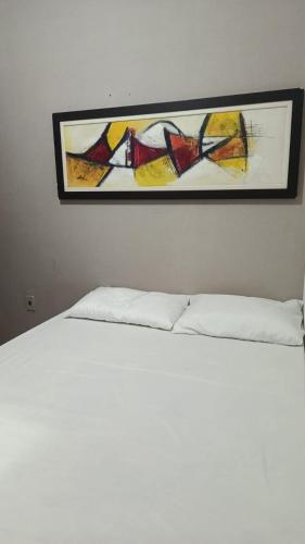 a painting hanging above a bed in a bedroom at Casa Conforto e Aconchego com garagem e internet próximo ao centro in Pesqueira