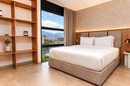 a bedroom with a large bed and a large window at Metropolitan Living by HOUSY in Medellín