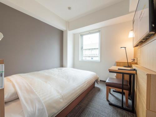 a small bedroom with a bed and a desk at Super Hotel Kokuraeki Minamiguchi in Kitakyushu