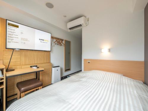 a bedroom with a bed and a projection screen at Super Hotel Kokuraeki Minamiguchi in Kitakyushu