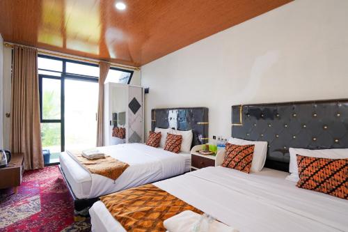 a hotel room with two beds and a window at The Lavana Astungkara in Beran-kidul