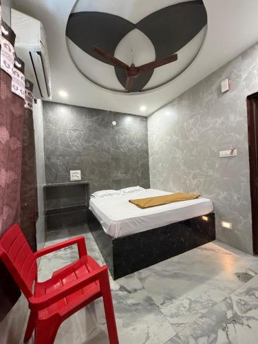 a bedroom with a bed and a red chair at Aditya Residency in Mādhavaram