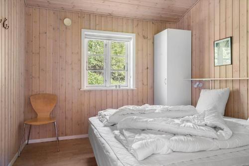 a bedroom with a bed with a window and a chair at 2608-Romo-Sonderstrandvej-18 in Høm