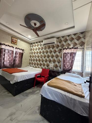 a bedroom with two beds and a red chair at Aditya Residency in Mādhavaram