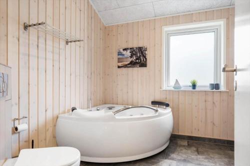 a bathroom with a tub and a toilet and a window at 2807-Romo-A-Hveyselsvej-28 in Høm