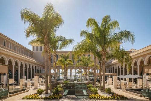 a courtyard with palm trees in a building at Gran Meliá Palacio de Isora Resort & Spa in Alcalá