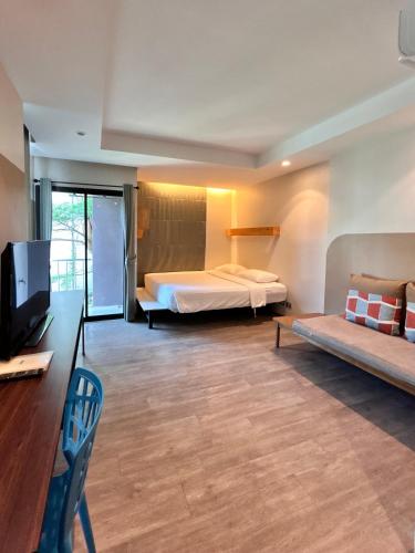 a bedroom with a bed and a tv and a couch at Varrzon Residence Srinakarin 56 in Bangna