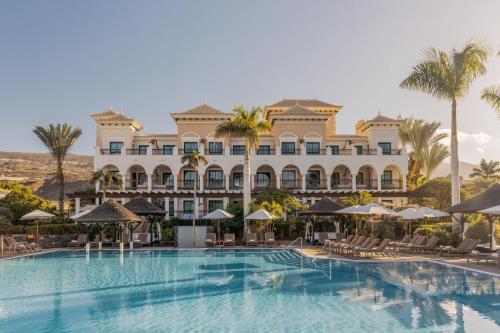 a hotel with a swimming pool and palm trees at RedLevel at Gran Meliá Palacio de Isora - Adults Only in Alcalá