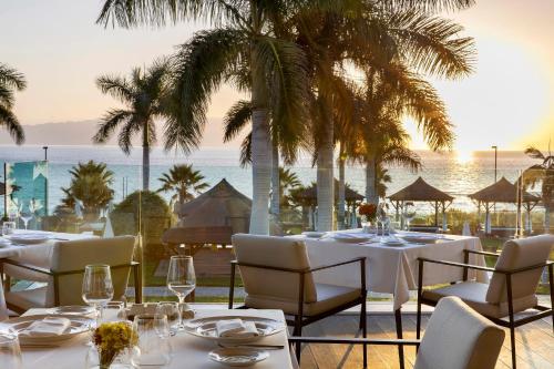 a restaurant with white tables and chairs and the ocean at RedLevel at Gran Meliá Palacio de Isora - Adults Only in Alcalá