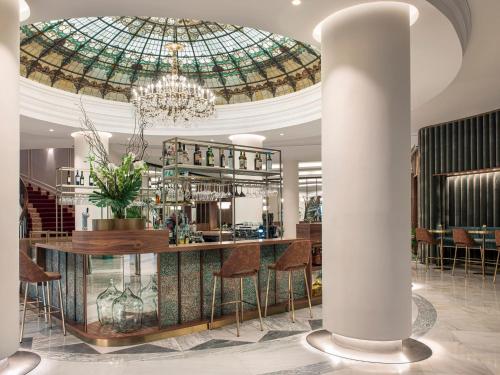 a lobby with a bar and a chandelier at Hotel Colón, a Gran Meliá Hotel - The Leading Hotels of the World in Seville