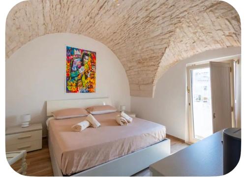 a bedroom with a bed with a painting on the wall at Rooftop Maisonette - Old Town by TrulloVista in Martina Franca