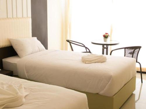 two beds in a room with a table and a table at The Capital Hotel in Roi Et